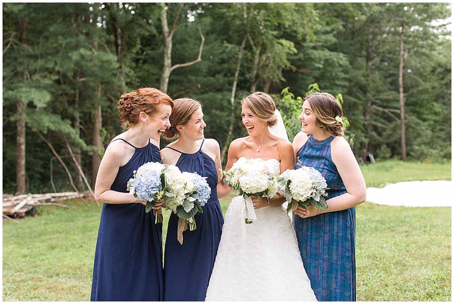 bride and bridesmaids in navy share a laugh 