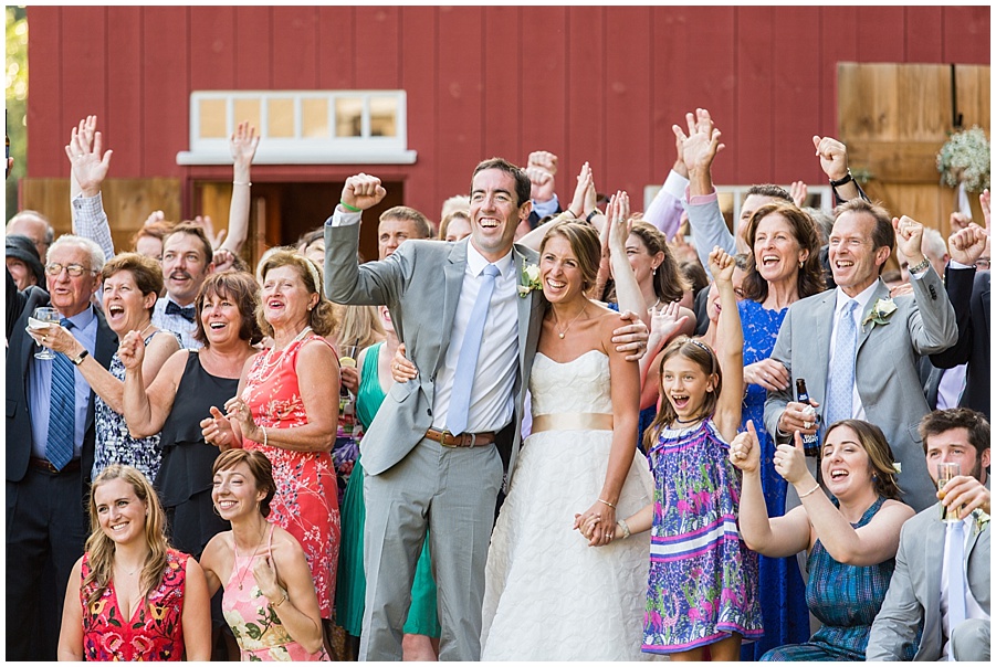 group shot of wedding guests in front of red barn 