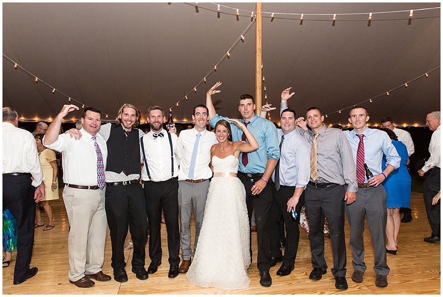 bride and groom pose with group of friends at reception 