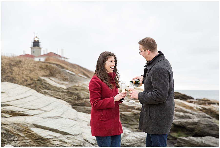 Couple pops bottle of champagne in front of Beavertail Lighthouse