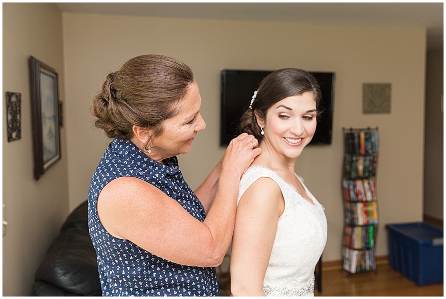 mom putting on daughters necklace before wedding