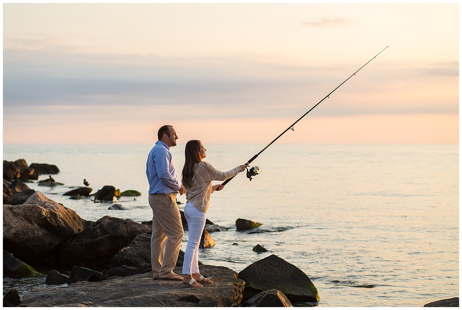 engaged couple fishing on the rock jetty in matunuck